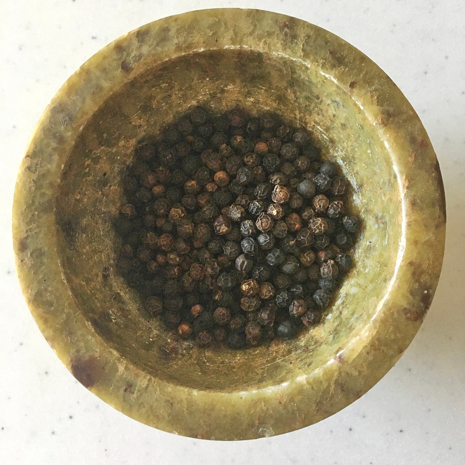 Black peppercorns in a stone mortar